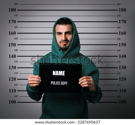 Criminal mugshot. Arrested man with blank card against height chart Royalty-Free Stock Photo #2287690637
