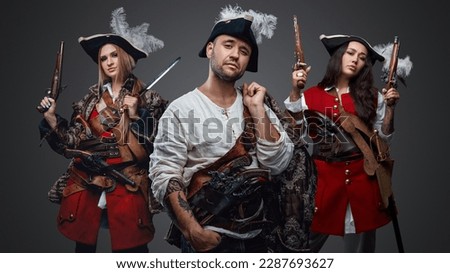 Shot of isolated on gray handsome corsair man and two pirates women.
