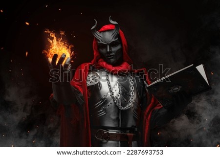 Portrait of evil sorcerer with fireball dressed in red robe and horned mask. Royalty-Free Stock Photo #2287693753