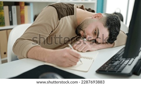Young arab man student tired writing on notebook at university classroom