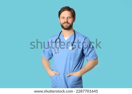 Happy doctor or medical assistant (male nurse) with stethoscope on turquoise background