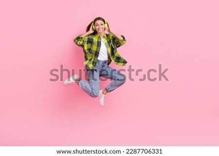Full length photo of optimistic woman long hairstyle wear checkered shirt touch headphones flying isolated on pink color background