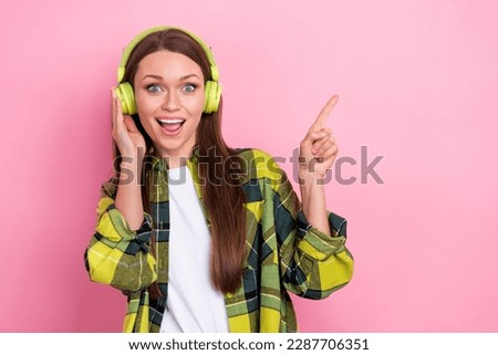 Portrait of cute positive lady hand touch headphones direct finger empty space isolated on pink color background