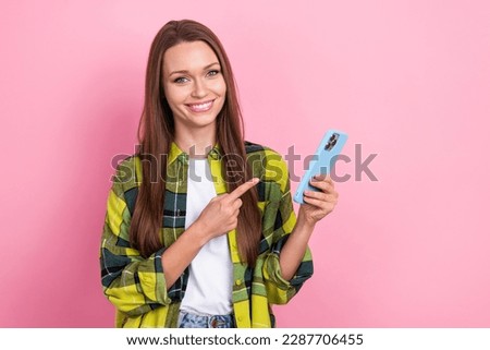 Photo of cheerful nice lady indicate finger hand hold smart phone isolated on pink color background