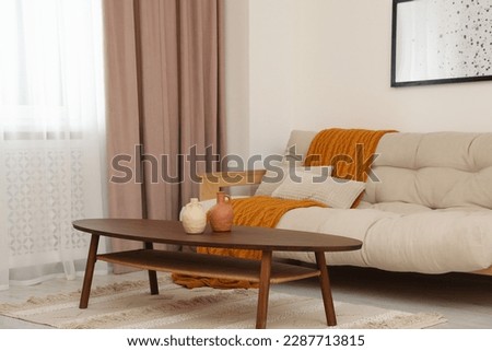 Living room with pastel window curtain, wooden table and sofa