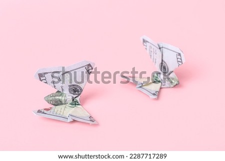 Origami butterflies made of dollar banknotes on pink background, closeup