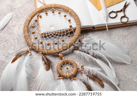 Dream catcher with book on grunge background, closeup
