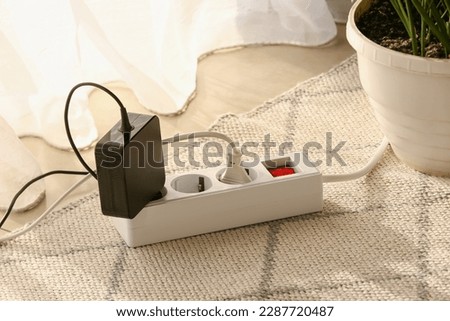 Electric extension cord with plugs on carpet Royalty-Free Stock Photo #2287720487
