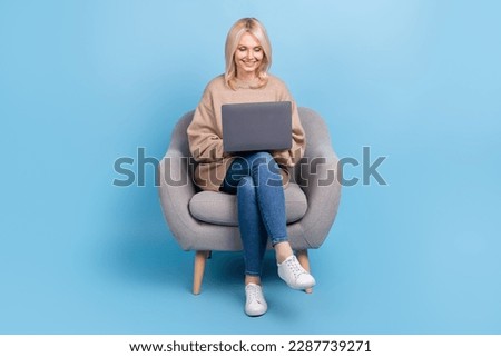 Full body cadre of satisfied it company team leader retired lady sitting armchair hold laptop coworking isolated on blue color background
