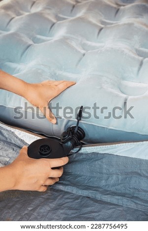 Closeup view of a woman inflating an air mattress inside the tent. Camping holiday and outdoor summer vacation. Lifestyle concept Royalty-Free Stock Photo #2287756495