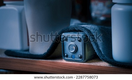 closeup hidden or spy camera under cloth on wooden shelf in dark room. Spy or detective or scandal concept.