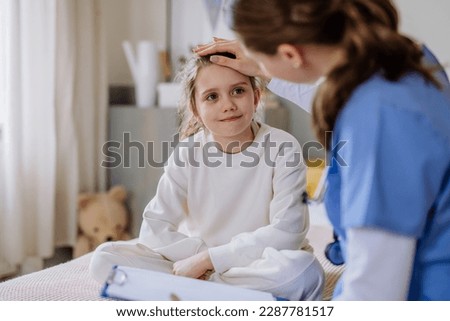 Young doctor taking care of little girl in hospital room.