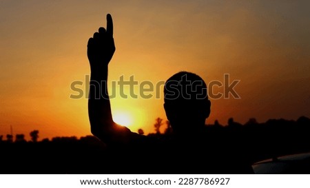 silhouette of a person pointing up giving a symbol in the afternoon