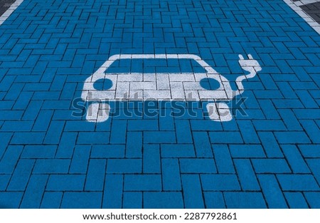 White electric vehicle symbol on blue floor of a charging station