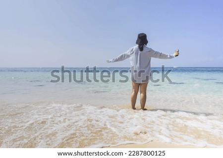 Photo of a woman standing alone at Beach during the day. Girl standing at sandy beach while sunny day.