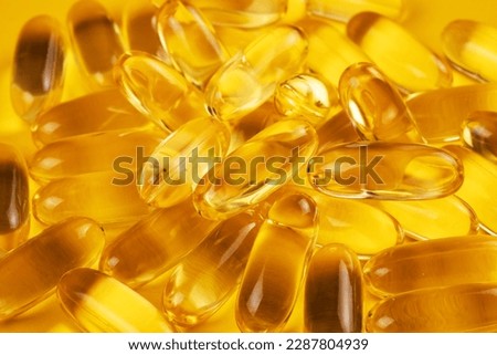 Fish oil capsules with omega 3 and vitamin D on yellow background. Royalty-Free Stock Photo #2287804939
