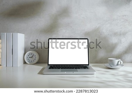 Minimal workplace with laptop computer, books and coffee cup on white working desk.