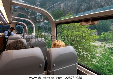 Passengers in the Rocky Mountaineer gold leaf 360 degrees panoramic train wagon along Fraser River, British Columbia, Canada. Royalty-Free Stock Photo #2287840661
