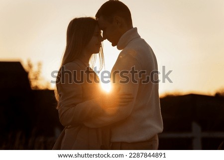 Silhouette of loving couple couple at sunset is hugging and touching nose to nose outdoors at park. Young man and woman falling in love have romantic date on Valentine's day. Royalty-Free Stock Photo #2287844891