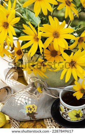 Blooming Jerusalem artichokes plant flowers in vase, in nature background, still life with  flowering Jerusalem artishokes on yellow table Royalty-Free Stock Photo #2287849617