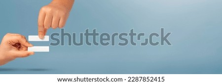 The symbol is equal in the hands of a child on a blue background. Two hands with an equals sign show a sign meaning equality. The concept of equal rights. Stop racism. Equal rights for men and women. Royalty-Free Stock Photo #2287852415
