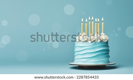 Birthday cake with blue frosting and yellow birthday candles ready for a birthday party, blue background Royalty-Free Stock Photo #2287854433