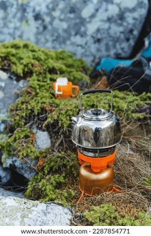 Boil water on a gas burner in the mountains, camping equipment for cooking, cook food in the mountains, brew coffee in nature, camping in the forest. High quality photo
