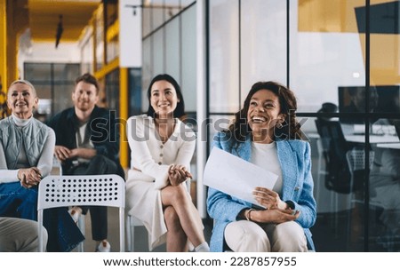 Cheerful male and female employees laughing during coaching and training conference in office room, successful colleagues brainstorming and smiling during leadership seminar in enterprise workspace Royalty-Free Stock Photo #2287857955