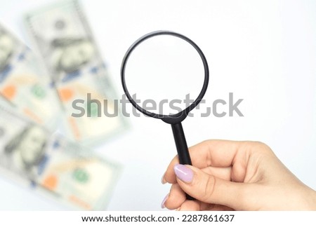 Selective focus. Magnifying glass and money - lies on american dollars on white, business background. The concept of poverty and the search for money, the search for earnings. High quality photo