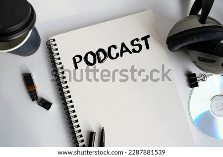 The inscription in the notebook PODCAST. Quiet workplace with coffee, headphones and notebooks. A moment of relaxation and disconnection with relaxing music. View from above.