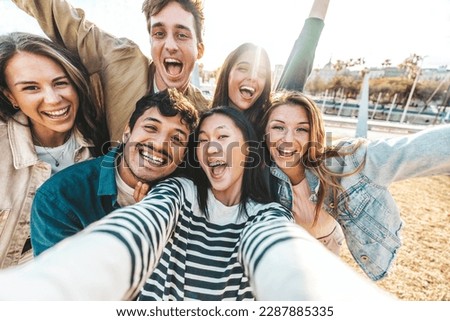 Multiracial friends taking selfie group outside - Millenial people laughing together at camera - University students having fun in college campus - Friendship and youth community concept