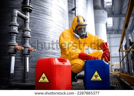 Chemicals industry production. Fully protected worker in yellow suit, gas mask, gloves and boots working with hazardous waste. Royalty-Free Stock Photo #2287885377