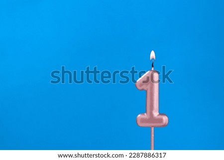 Number 1 - Burning anniversary candle on blue foamy background Royalty-Free Stock Photo #2287886317