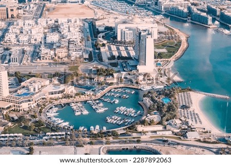 A stunning aerial shot of the marina, with its sparkling blue waters and sleek luxury yachts lined up in neat rows against the backdrop of the city skyline.