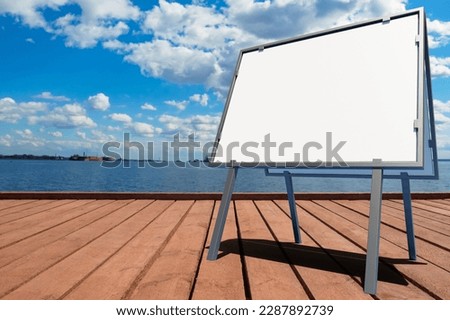 Advertising sign. Empty rack on pier. Seascape view from shore. Place for inscription. Signboard is portable. Empty billboard for advertising. Signboard on sea coast. Mock up, template. 