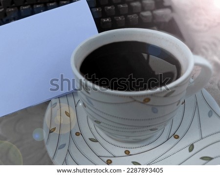 Closeup of a cup of black coffee with blank white notepaper and old typewriter keyboard. Copy space for business and personal reminder notes concept. Royalty-Free Stock Photo #2287893405