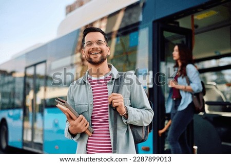 Young happy man getting out off a bus at city station.  Royalty-Free Stock Photo #2287899013
