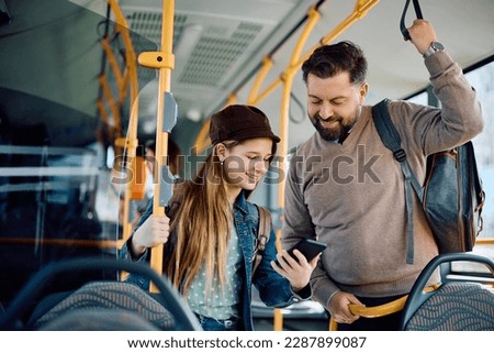 Happy father and daughter using app on mart phone while commuting by public transport.  Royalty-Free Stock Photo #2287899087