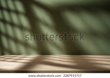 Empty table on khaki green texture wall background. Composition with grid shadow on the wall and light reflections. Mock up for presentation, branding products, cosmetics food or jewelry.