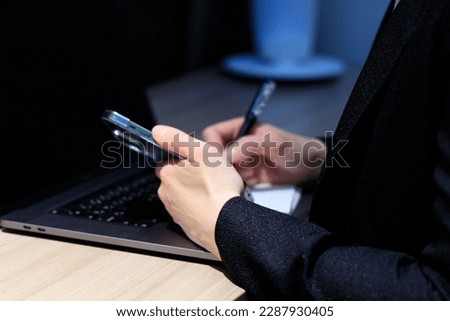 A woman working using a computer and a smartphone