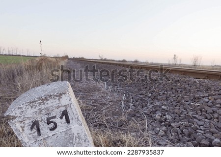 Milestone next to rural railroad tracks