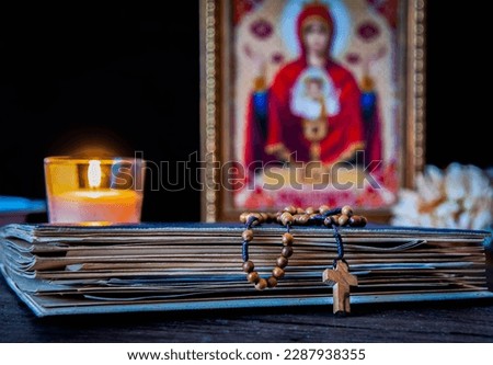 The time for prayer. Wooden Rosary on an ancient prayer book. Icon of the Mother of God and Jesus. Lighted candle. Royalty-Free Stock Photo #2287938355