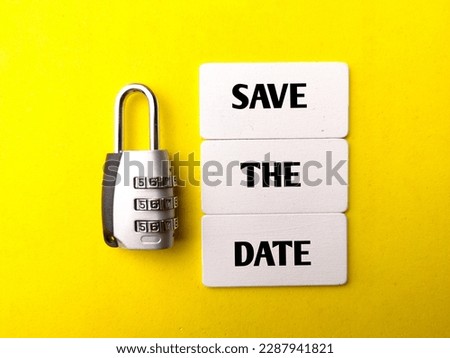 Padlock and wooden board with the word SAVE THE DATE on a yellow background. Business concept.