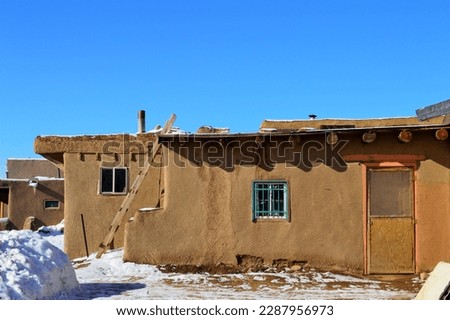 Adobe structure during winter with turquois window frame.  Royalty-Free Stock Photo #2287956973