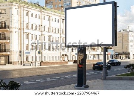 Billboard in the city in the summer near the road against the backdrop of a light building. Mock-up.