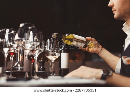 Bartender pouring sparkling white wine into wineglasses. Royalty-Free Stock Photo #2287985351