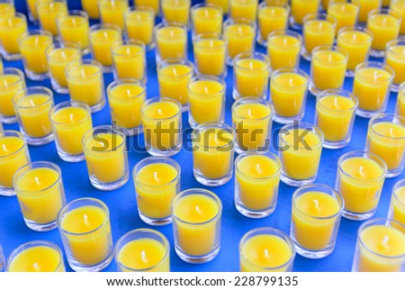 MANY CANDLES GLASS ON THE BLUE TABLE.