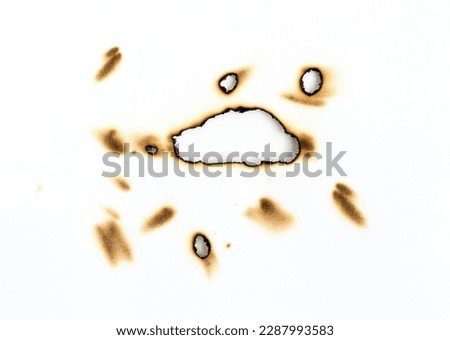 Fire holes on white paper burning of paper, texture and background Royalty-Free Stock Photo #2287993583