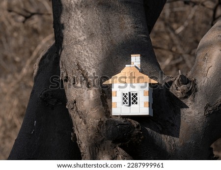 Small brick toy house on the branches of a large tree