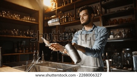Authentic professional caucasian bartender flaring his shaker before making a cocktail. Experienced barman juggling with his equipment - food and drink  Royalty-Free Stock Photo #2288006327